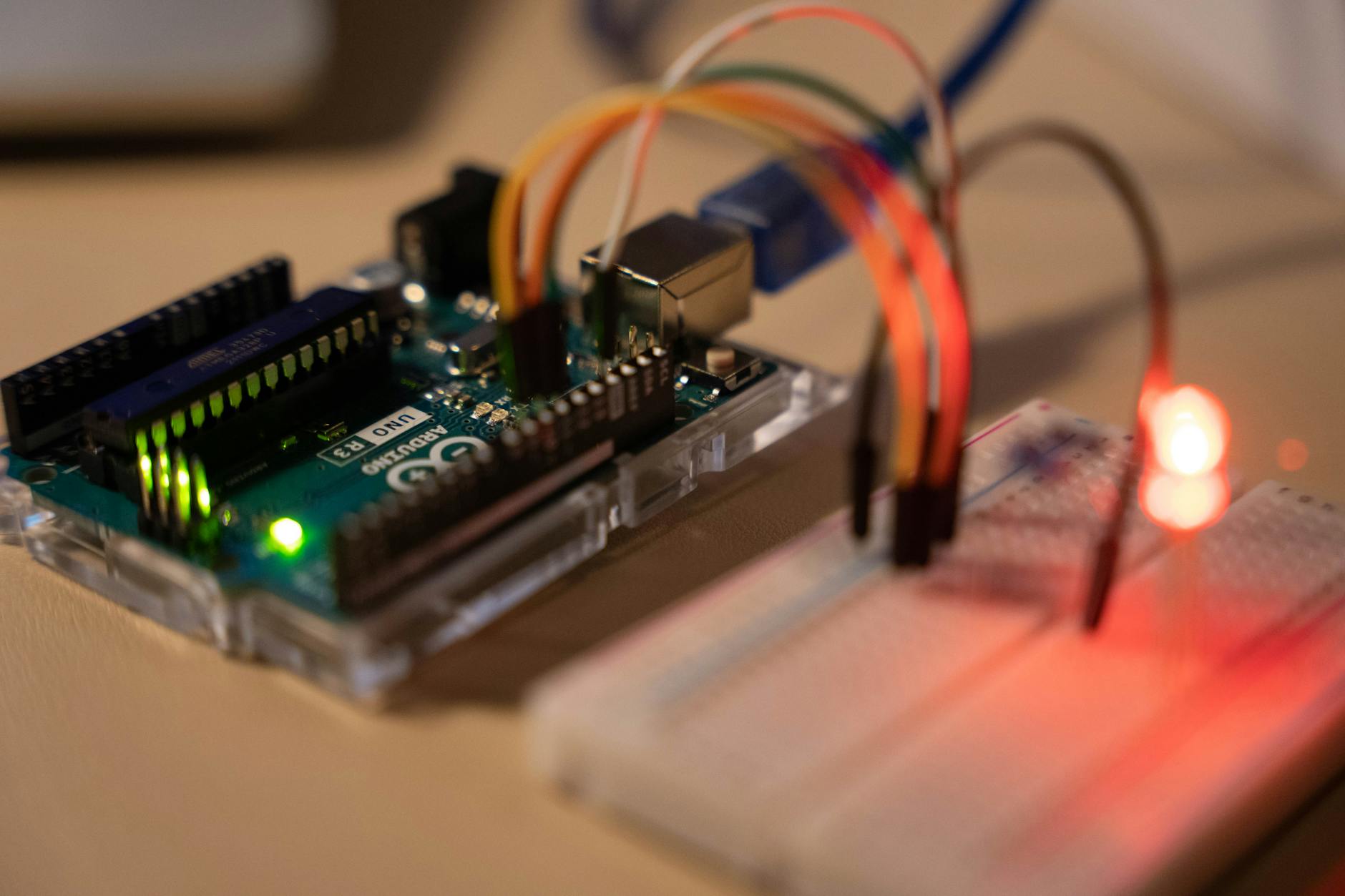 Zbliżenie na Arduino z podłączoną płytką stykową i świecącą diodą LED
