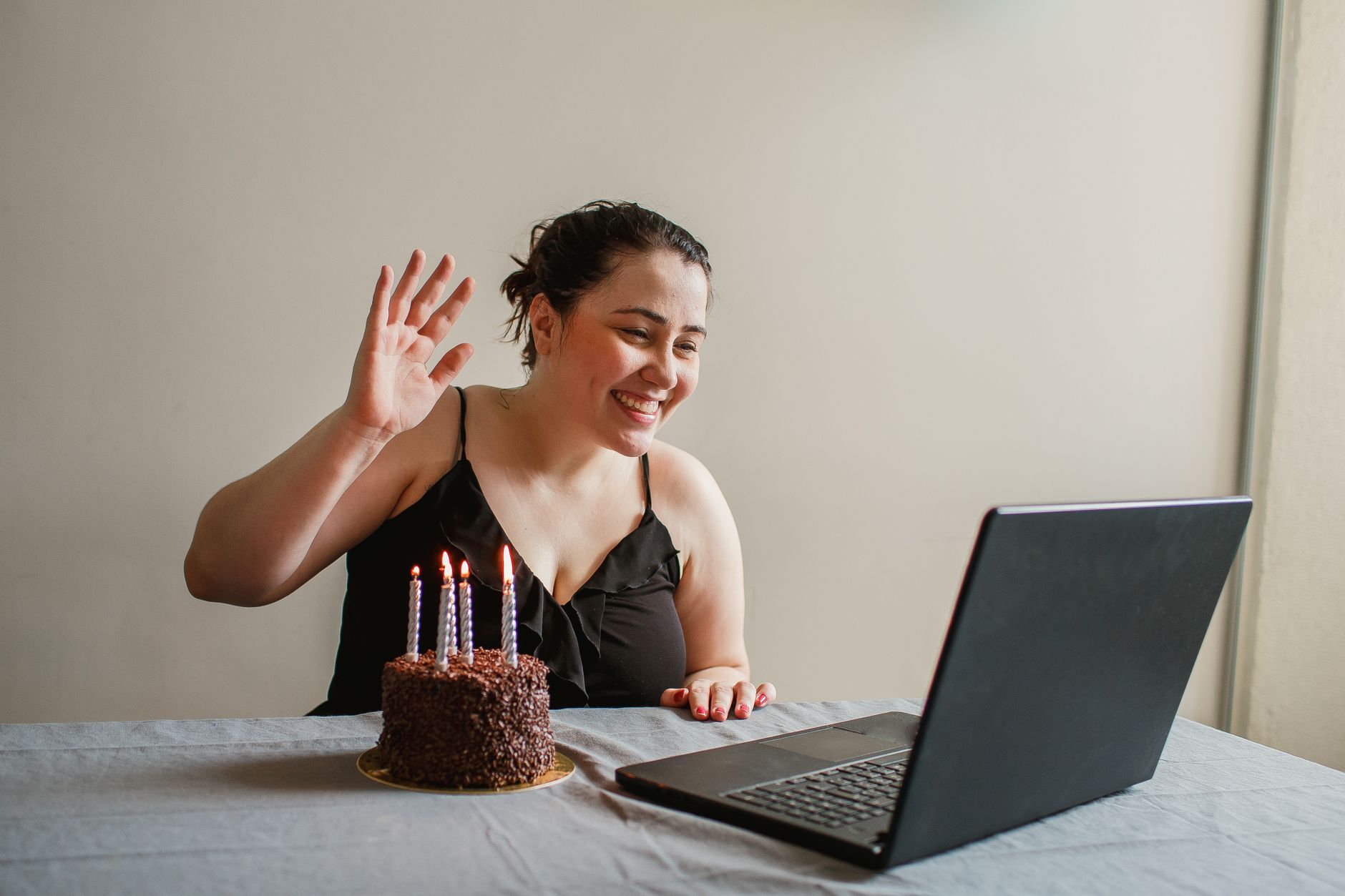 Kobieta świętuje urodziny online z tortem przed laptopem