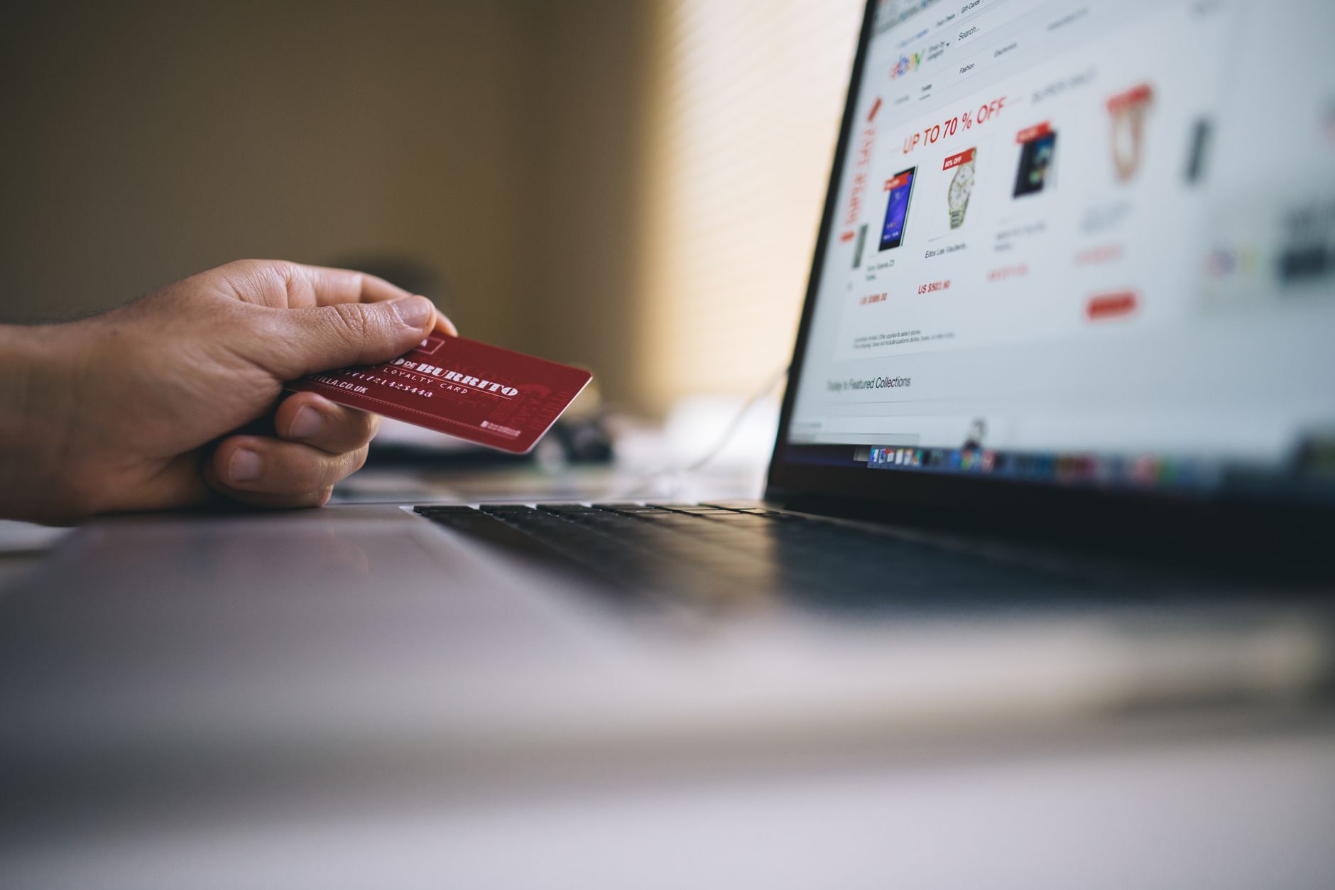 Bezpieczne płatności w internecie: karta wirtualna, Apple Pay, Google Pay i limity transakcji Osoba trzyma kartę płatniczą podczas zakupów online na laptopie
