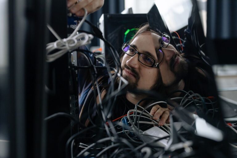 Informatyk porządkujący splątane kable przy stanowisku pracy