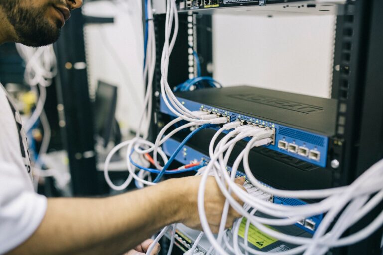 Specjalista IT podłącza kable Ethernet w szafie serwerowej